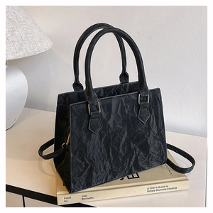 Detail of black PU handbag with unique crinkled texture and golden hardware accents