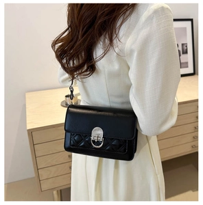 Detail of a black quilted leather crossbody bag with silver twist-lock on a model