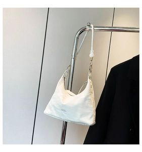 Close-up of white hobo bag with wrinkled texture and decorative beads on shoulder strap