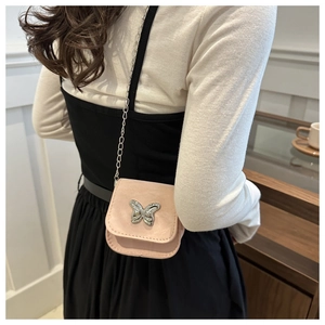 Detail van roze suède mini crossbodytas met zilveren vlinder en metalen ketting