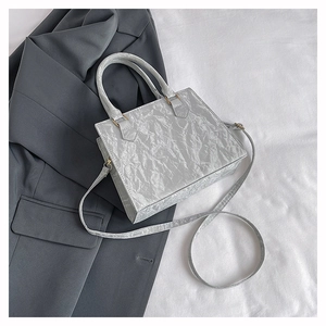 Detail showing grey textured PU handbag with pleated surface and detachable shoulder strap