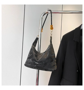 Detail of black wrinkled tote bag with amber bead accent and classic woven label