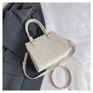 Detailed view of white pleated PU leather handbag with matte texture and gold hardware