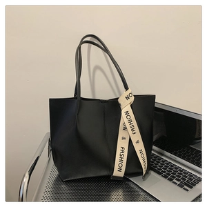 Close-up of black leather tote bag featuring a beige fashion ribbon and large capacity