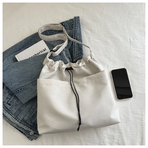 Detailed view of white drawstring oxford fabric bucket bag with side pocket and strap