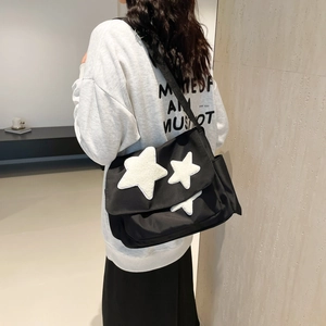 Cute black messenger bag with white star patches and wide strap for daily school use