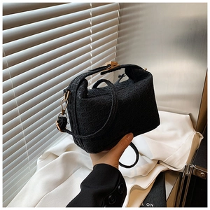 Detail of black woven handbag showing fine texture and luxury gold-tone hardware hooks