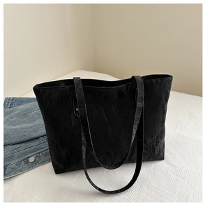 Close-up of black tote bag with unique wrinkled texture and glossy minimalist finish