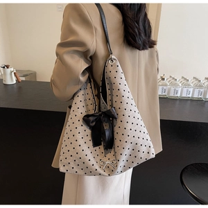 Chic tote bag featuring black heart polka dots and a silk bow on an elegant model
