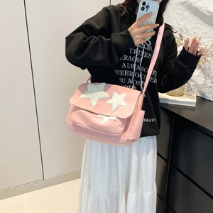 Pink messenger bag with white star patches and wide shoulder strap for women