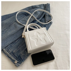 Detail of white star embossed mini crossbody bag shown next to a smartphone for size reference