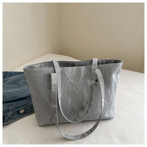Detail of silver gray tote bag with crinkled texture on a minimalist bed setting