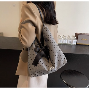 Detail of grey heart-pattern tote bag with a large black bow and metallic butterfly charm
