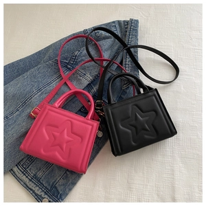 Detailed view of pink and black star-embossed square bags on a denim jacket background