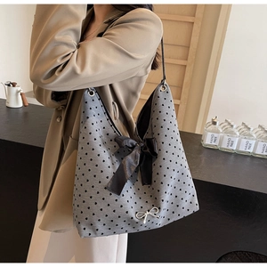 Close-up of heart print canvas tote bag featuring a large black satin bow and metal charm