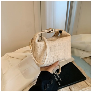 Detailed macro view of woven texture and gold metal buckle on cream shoulder bag