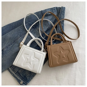Detail of mini square bags in white and brown with embossed star design and gold hardware