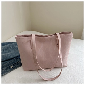 Detail of pink tote bag with pleated texture shown alongside a blue denim jacket