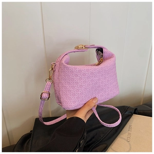 Close-up of purple woven texture on handbag with pale gold metal buckle and strap