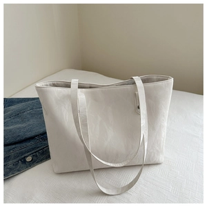 Detail of white large capacity tote bag with glossy wrinkled texture on white bedding