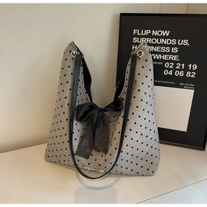 Detail of grey knitted tote bag featuring black heart patterns and a large satin bow