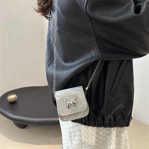 Zilveren mini crossbodytas met vlinder metalen accent en kettingriem bij een model