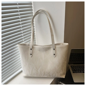 Detail of white textured tote bag with crinkle finish and laptop in natural office light