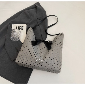 Detailed view of silver bow charm and black ribbon on gray heart pattern tote bag