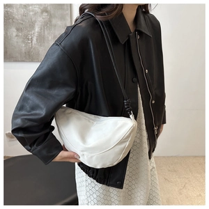 Primer plano de un bolso bandolera blanco de media luna con nudo llevado por modelo