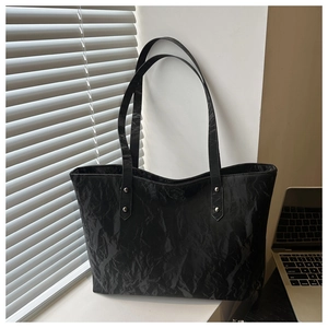 Detail shot of black tote bag showing unique crinkle texture and silver rivet hardware