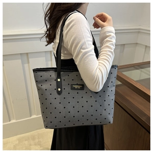 Detail of grey polka dot tote bag showing texture, fashion label and long black shoulder strap