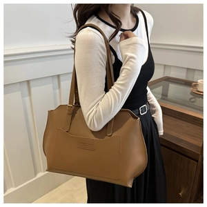 Détail d'un sac cabas marron en cuir avec poche avant et gravure de logo chic