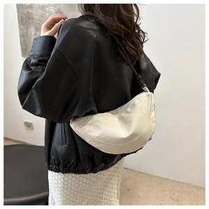 Detalle de un bolso de media luna blanco minimalista de nailon con correa negra ajustable
