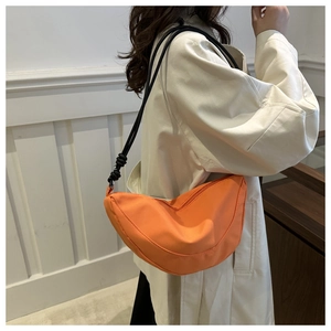 Detalle de bolso media luna de nailon naranja con correa de nudo negro y cierre de cremallera