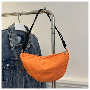 Detalle de bolso media luna de nailon naranja con correa de cuerda negra en percha