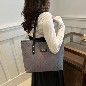 Grey fabric tote bag with red heart patterns and black straps shown on a model