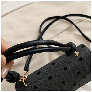 Detail von schwarzem Chevron-Gewebe mit 3D-Punkten und Ledergriffen an Handtasche