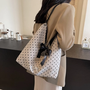 Chic grey heart print tote bag with large black satin bow worn by model in a cafe