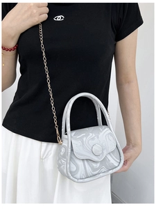 Detail of gray marble pattern crossbody bag with golden chain strap on a model