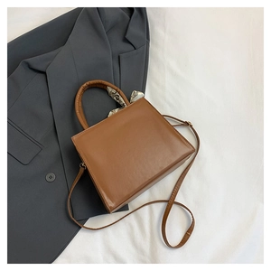 Sac à main carré en cuir marron avec anse enroulée d'un foulard sur fond blanc épuré