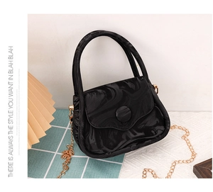 Detail of black marble textured handbag with magnetic clasp and gold chain strap