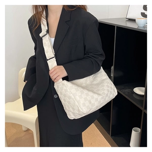 Gros plan détaillé d'un sac cabas à carreaux blancs avec bandoulière réglable sur un blazer noir