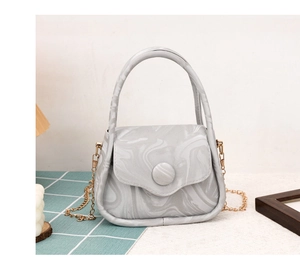 Detail view of light grey marble pattern mini bag with gold chain strap on checkered cloth