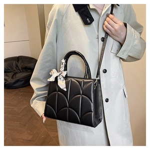 Détail d'un sac à main noir matelassé avec poignée en foulard élégant et bandoulière
