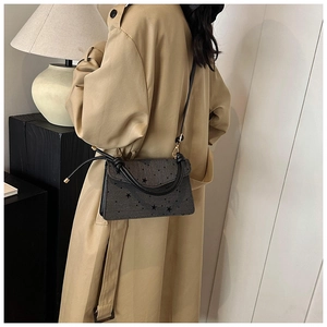 Detailansicht einer grauen Handtasche mit Sternenprint, getragen zum beigen Trenchcoat