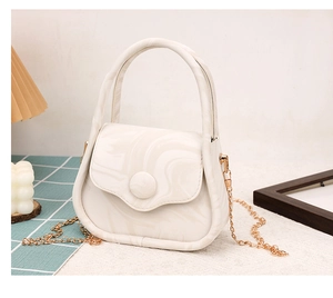 Detailed shot of white marble pattern crossbody bag with golden chain in elegant setting