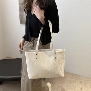 Minimalist cream tote bag with ruched texture and rivet details for daily commute