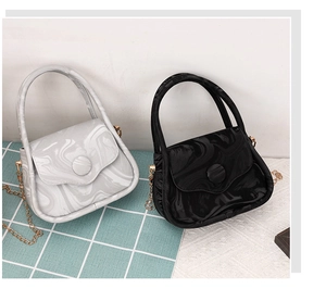 Detail of marble-textured crossbody bags with gold chain and round button closure