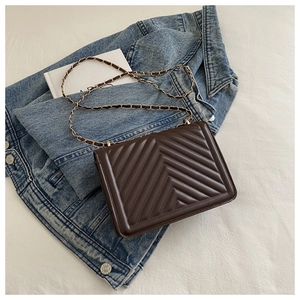 Detailed close-up of a dark brown V-quilted faux leather crossbody bag with gold chain strap