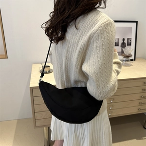 Bolso medialuna negro en tejido Oxford llevado al hombro por una modelo femenina